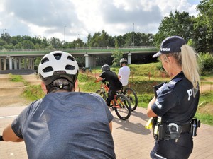 policjantka stoi obok grupy osób na rowerach podczas treningu na rowerowym torze zjazdowym