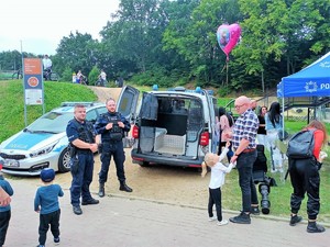 policjanci pozują obok policyjnego radiowozu, prezentują więźniarkę uczestnikom festynu