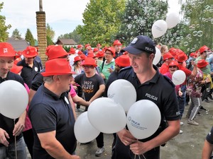 policjant rozdaje balony osobom bawiącym się przed sceną podczas festynu