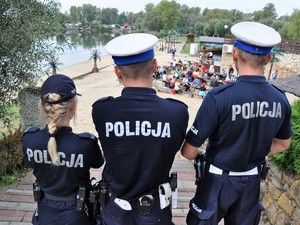 policjantka i dwóch policjantów stoją na schodach prowadzących na plażę zbiornika wodnego