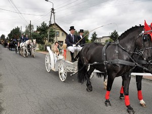 ulicą przejeżdża dorożka z woźnicą i pasażerami