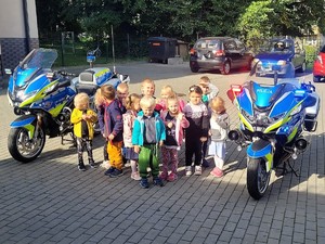 pomiędzy policyjnymi motocyklami stoi grupa przedszkolaków