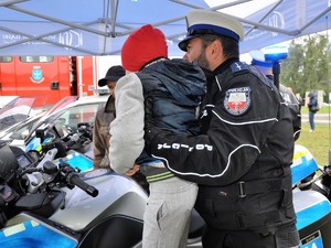 policjant podnosi dziecko, aby zobaczyło z bliska policyjny motocykl