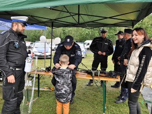 policjant przekazuje odblaskową smycz chłopcu, obok niego stoi drugi policjant i kobieta