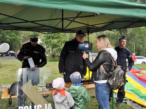 przed policjantem stoi kobieta, patrzy przez policyjny radar, obok niej stoi dwójka dzieci