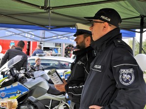 policjanci stoją obok siebie, jeden z nich trzyma w rękach puszkę charytatywną