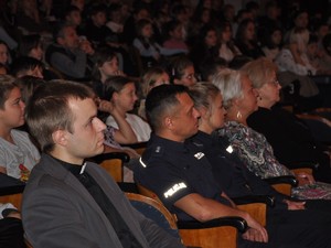na sali kinowej siedzą uczniowie i w pierwszym rzędzie ksiądz, policjant, policjantka i kobiety