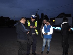 obok siebie stoją policjant, trzy kobiety i młody mężczyzna, kobiety trzymają elementy odblaskowe