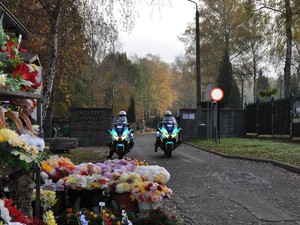 policjanci na motocyklach stoją przed wejściem na cmentarz