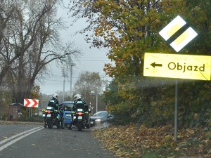 na drodze stoją obok siebie dwa policyjne motocykle, przed nimi widać znak z napisem objazd