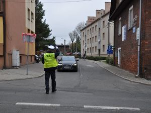 na skrzyżowaniu stoi policjant, kieruje ruchem