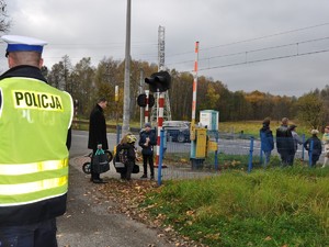 osoby wracają z cmentarza, na pierwszym planie widać policjanta stojącego tyłem