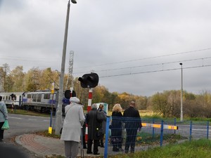 osoby oczekują na przejazd pociągu