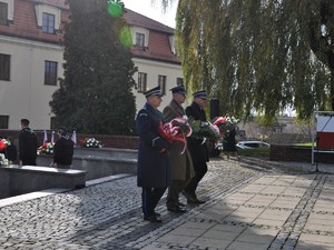 zdjęcie przedstawia przedstawicieli służb, którzy zmierzają z kwiatami pod pomnikiem Powstańców Śląskich