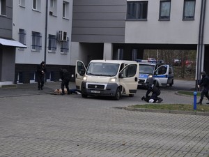 policjanci celują z broni do napastnika, który kładzie się na ziemię