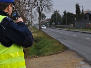 policjant przy drodze mierzy prędkość, z jaką poruszają się pojazdy