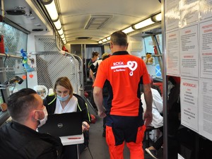 w ambulansie do oddawania krwi osoby oczekują na oddanie krwi, na zdjęciu, tyłem stoi ratownik medyczny