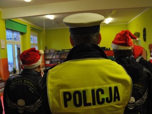 Zdjęcie przedstawia stojącego tyłem Policjanta w towarzystwie przedstawicieli grupy motocyklowej.
