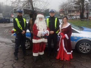 Zdjęcie przedstawia policjantów wraz z Mikołajem w tle znajduje się radiowóz.