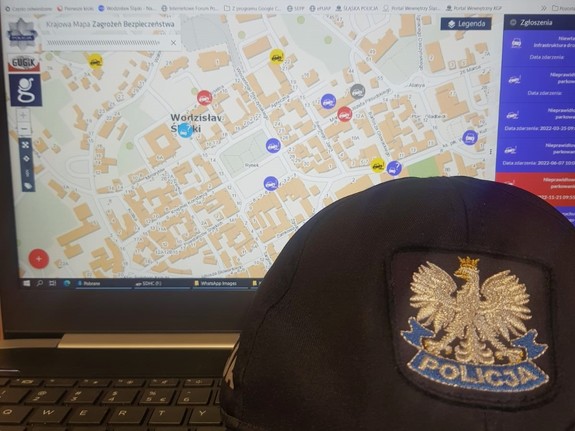 na zdjęciu widać pulpit laptopa, na którym wyświetla się krajowa mapa zagrożeń bezpieczeństwa, przed pulpitem znajduje się policyjna czapka