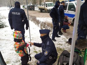 podczas festynu policjant kuca obok dziecka, pokazuje mu broń długą.