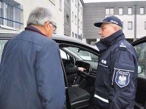 policjant rozmawia z samorządowcem obok nowego, nieoznakowanego radiowozu