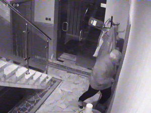 na zdjęciu widać mężczyznę stojącego obok drzwi, zdjęcie to klatka z zapisu monitoringu