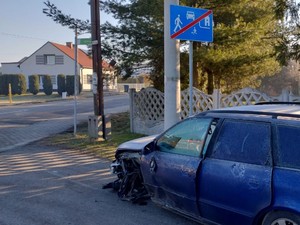 Na jezdni przed znakiem odwołującym strefę zamieszkania stoi uszkodzony samochód, pojazd brał udział w kolizji drogowej