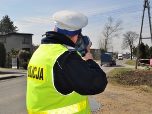 policjant mierzy prędkość, z jaką poruszają się pojazdy