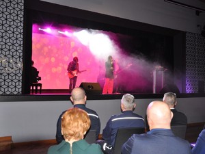 na scenie występuje kobieta, która śpiewa do mikrofonu, światło jest przyciemnione
