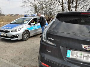przed radiowozem stoi mężczyzna, rozmawia z policjantem siedzącym wewnątrz