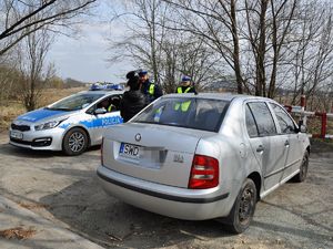obok radiowozu stoi samochód, przed nim stoi tyłem do zdjęcia kobieta, policjant stojący przed nią rozmawia z nią
