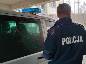 na tle radiowozu stoi policjant