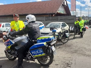 policjant siedzi na policyjnym motocyklu, obok niego stoi uczestnik rajdu rowerowego