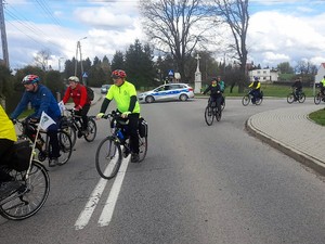 policyjny radiowóz stoi na drodze, trwa przejazd rowerzystów po drodze