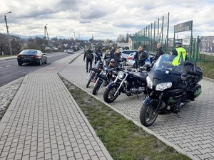 na parkingu samochodowym stoją zaparkowane motocykle, z motocyklistami rozmawia policjant