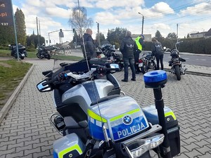 na parkingu samochodowym stoi zaparkowany policyjny motocykl, w tle widać kolejne motocykle