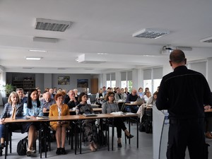 policjant prowadzi szkolenie, przed nim siedzi liczna grupa dyrektorów szkół