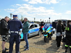 policjanci podczas festynu rozmawiają z jego uczestnikami, widać policyjny radiowóz i motocykl