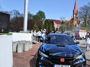 na przodzie widać tuningowany samochód, w tle widać Sznupka, który macha do dzieci