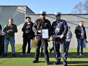 policjanci stoją na scenie, w rękach trzymają podziękowanie do organizatorów