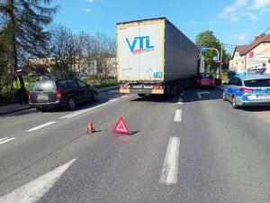 na jezdni stoi tir, który zahaczył o samochód osobowy, obok nich stoi radiowóz, policjant kieruje ruchem