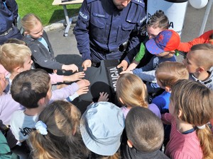 policjant pokazuje dzieciom kamizelkę kuloodporną, dzieci jej dotykają dłońmi