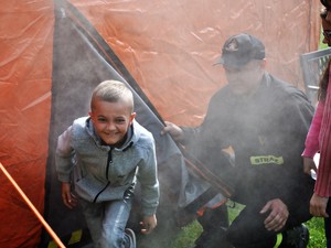 chłopiec wychodzi z namiotu pełnego dymu, drzwi uchyla mu strażak