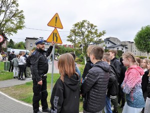 Na zdjęciu widać policjanta, który uczy młodzież rozpoznawać znaki drogowe.