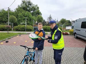 Zdjęcie przedstawia policjanta wręczający osobie nagrodę.