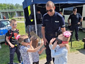 Na zdjęciu widać policjantów oraz dzieci w alkogoglach i narkogogleach