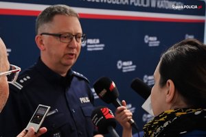 Na zdjęciu widać dziennikarzy, którzy przeprowadzają wywiad z policjantem