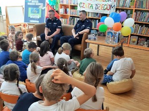 policjanci siedzą przed dziećmi w bibliotece