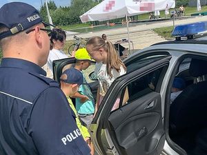 Na zdjęciu widać policjanta oraz grupę dzieci, które siedzą w radiowozie.